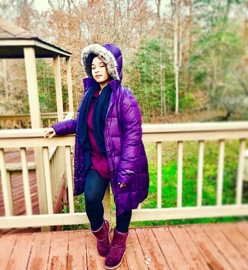 Person wearing a purple jacket outdoors in early fall before leaves fully changed.