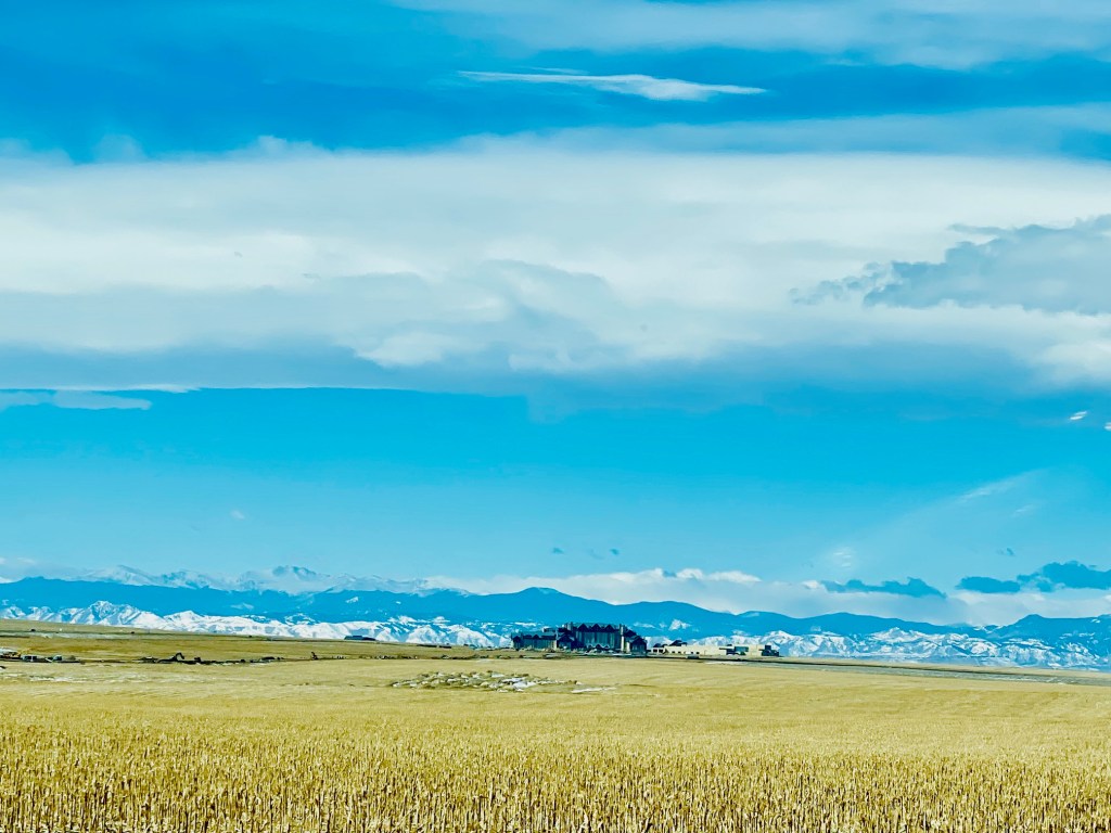 Hotel building in the distance with a Colorado mountain range behind it under clear morning skies.